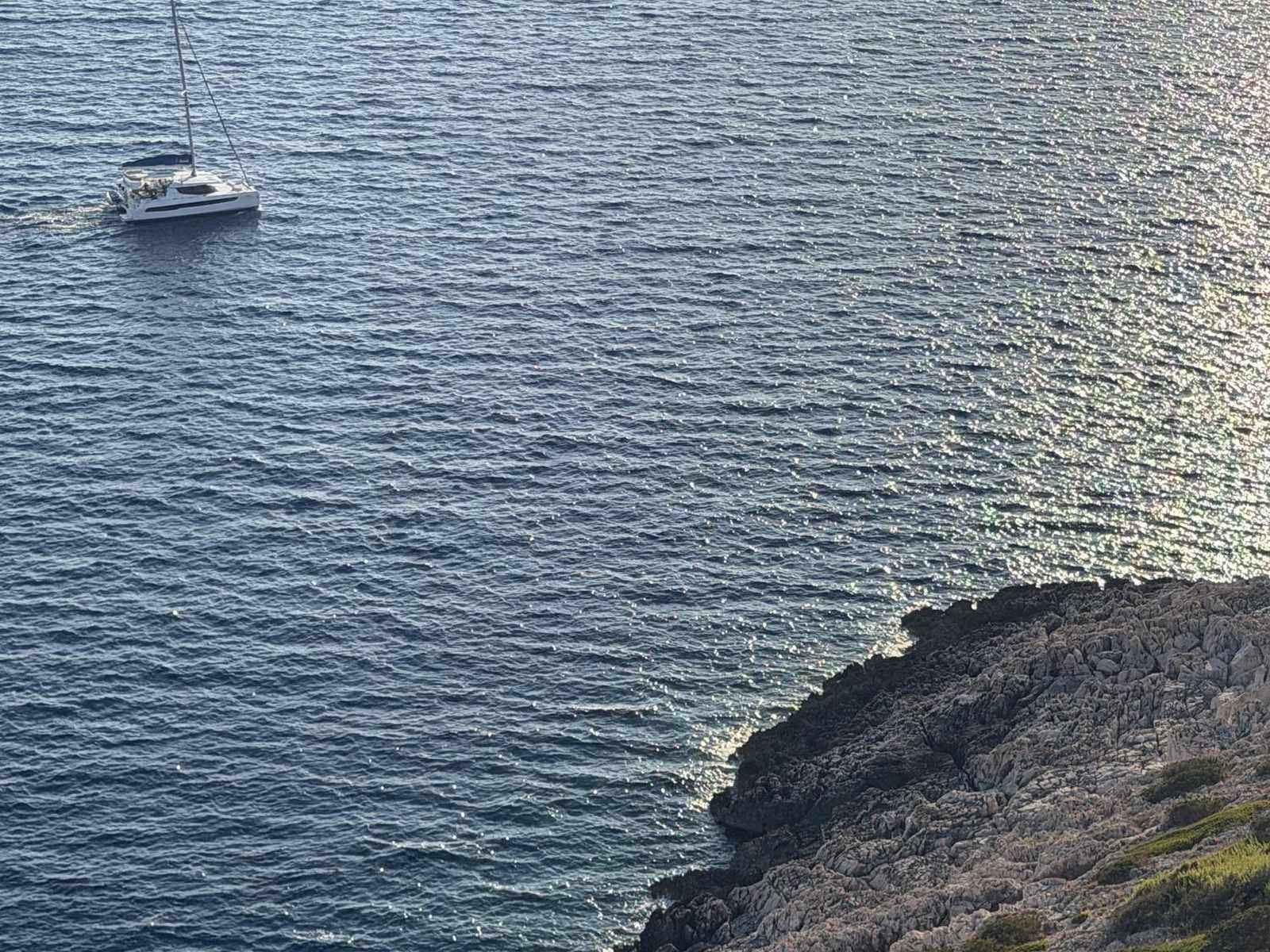 A sailing boat beside a steep rocky shore